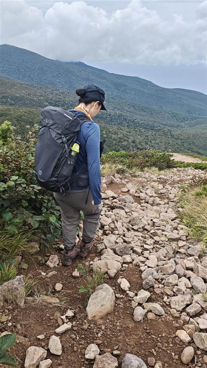 岩の道を下る後ろ姿。プロティウム35を背負っている