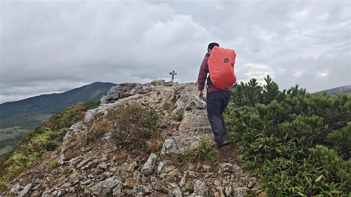 レインカバーをかけたプロティウム35を背負って、岩内岳の山頂へ向かう後ろ姿