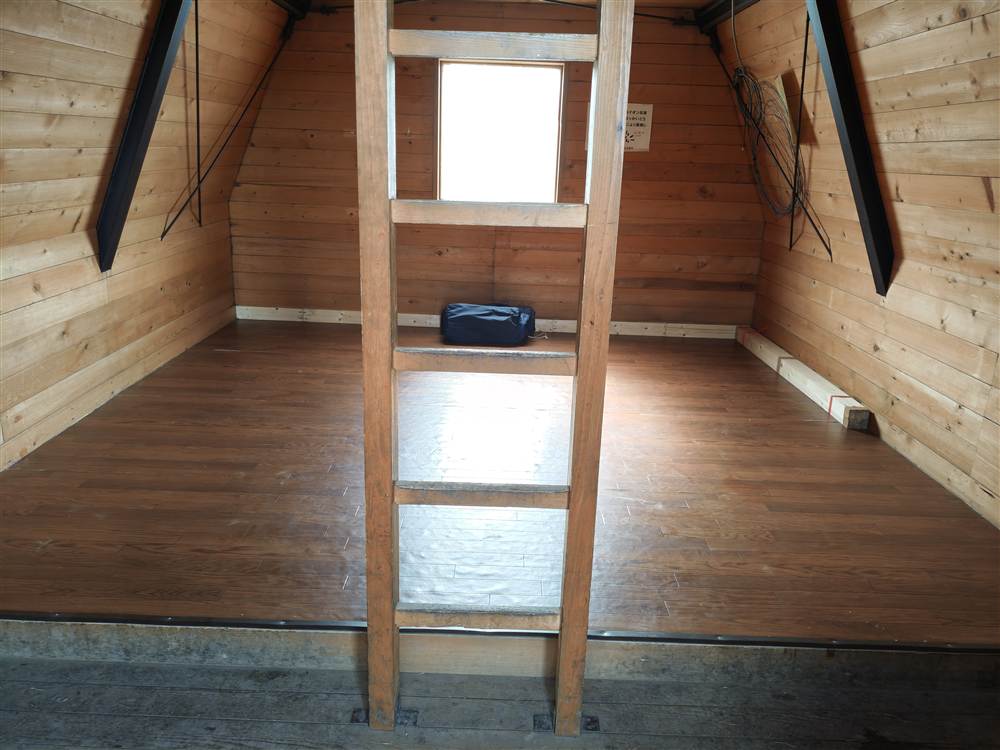 避難小屋の中。板の間と、上の階へのはしご