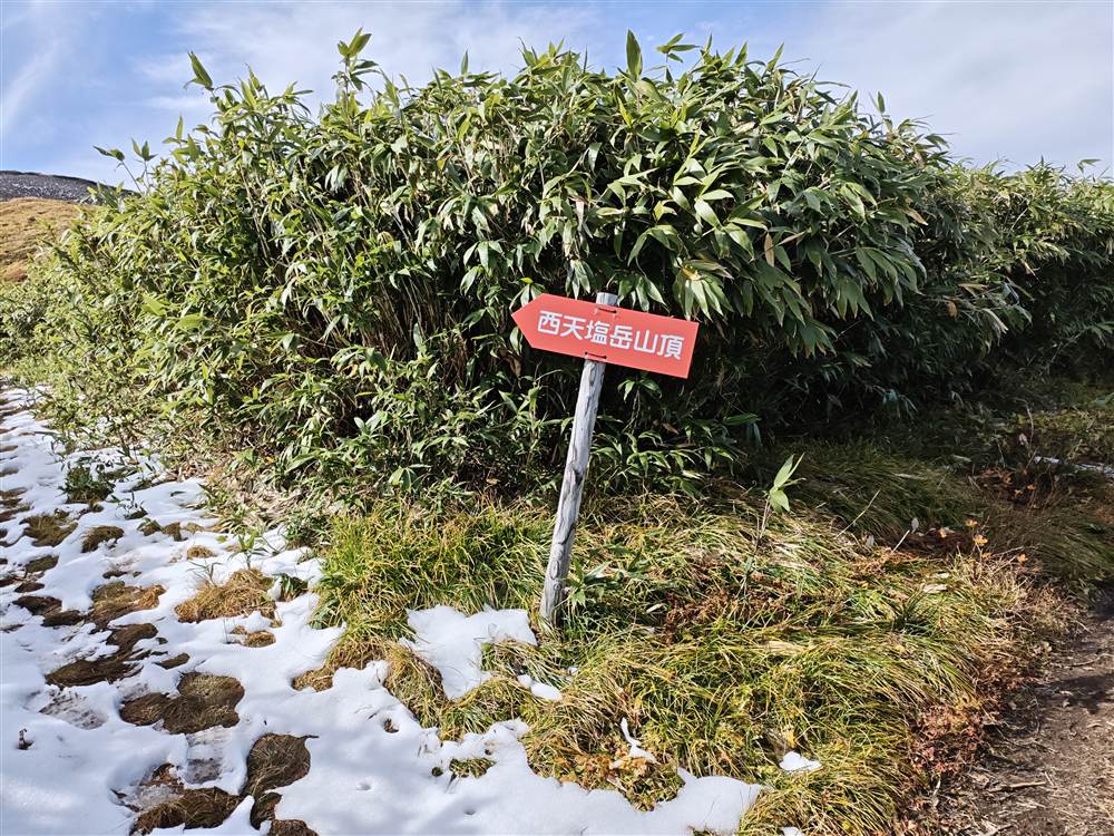 雪の残る道と西天塩岳山頂の標識